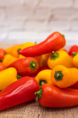 delicious and healthy red, orange and yellow sweet peppers on a wooden cooking board ready to be prepared in one recipe