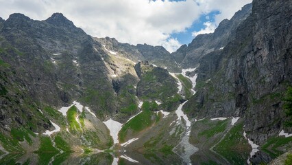 Reflection of the rocky mountains with snow against a cloudy sky in Morskie Oko, Poland © Wirestock