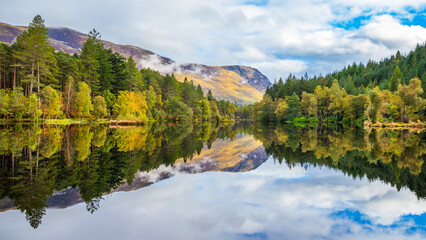 Perfect reflection on the lake Glencoe Lochan in Scotland, with autumn trees and mountain in the background