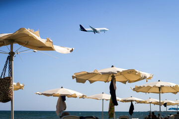 the plane lands over the sea, the beach. The plane flies over the beach umbrellas