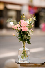 Pink and beige roses in a glass decanter on the street