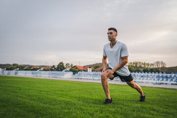 one man male athlete stretch outdoor at stadium track