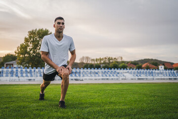 Naklejka premium one man male athlete stretch outdoor at stadium track