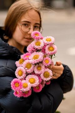 Girl with a pink bouquet stands in a portrait photo