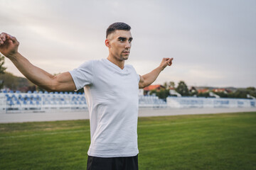 one man male athlete stretch outdoor at stadium track