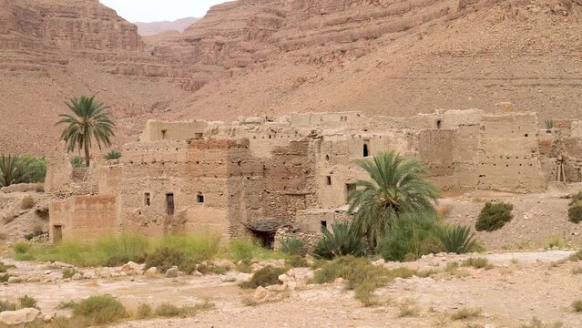 Traditional Moroccan clay houses with flat roofs, high clay walls and small windows in the Atlas mountain gorge by Ziz river, Morocco