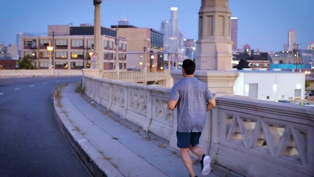Athletic Man working out by jogging across the 4th Street Bridge over the LA River near downtown Los Angeles.