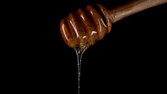 Organic honey flows olive wood dipper stick, tasty process. Apiary, beekeeping