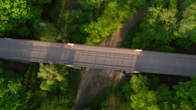 Birds eye view of a pedestrian bridge over a ravine and wooded path. 