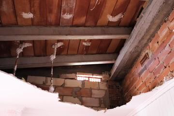 An interior ceiling has been breached, exposing the brick structure.