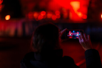 Hände halten ein Mobiltelefon bei einer Nachtaufnahme