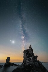 Person admires the tranquil beauty of the milky way galaxy sky from a cliff in Dalian, Liaoning