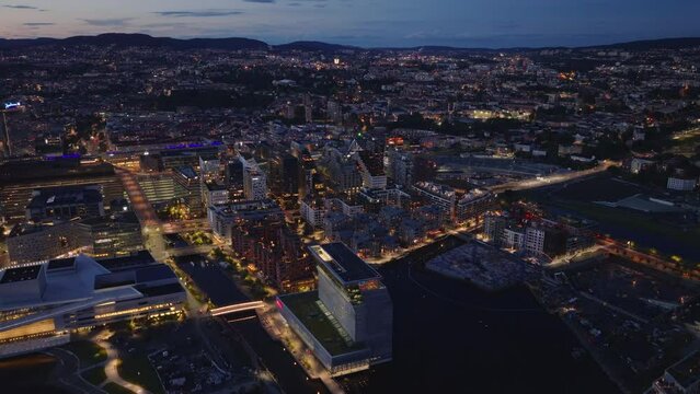 Aerial panoramic view of large city at dusk. Modern urban borough on waterfront, streetlights illuminating public place. Oslo, Norway