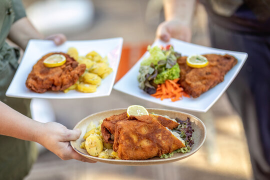 A waitress serving freshly prepared Cordon Bleu in different variations, view from above