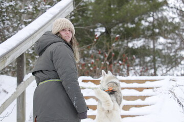Caucasian woman walking in a snowy park with her husky