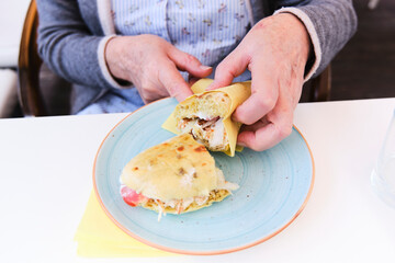 Hands of an Older Woman Holding a Sandwich in a Café