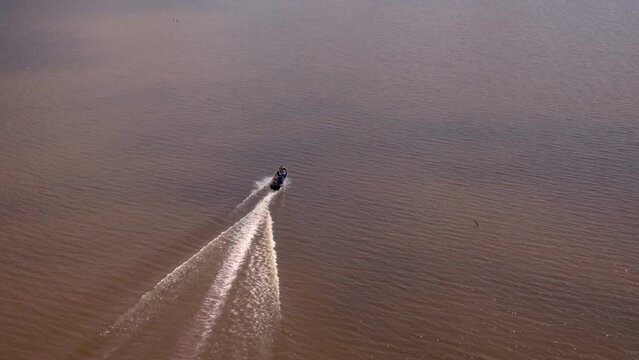 Aerial Forward Shot Of People Driving Motorboat In Rippled River On Sunny Day - Bayou, Louisiana