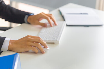 Closeup of male hand clicking wireless digital mouse working with desktop computer at office desk