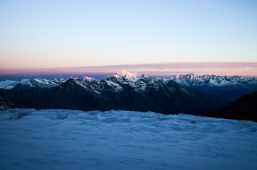 View over the snowy mountains with sharp peaks with the pink sunset in the background