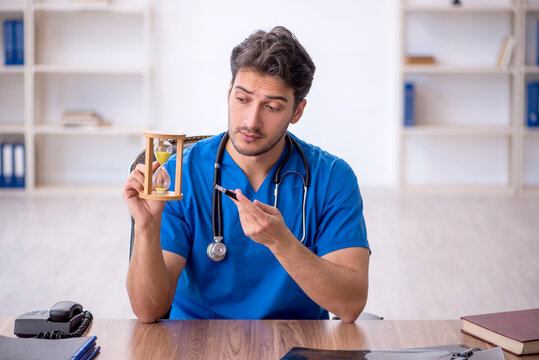 Young male doctor in time management concept
