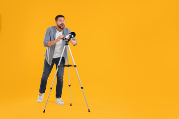 Happy astronomer with telescope on orange background. Space for text - obrazy, fototapety, plakaty