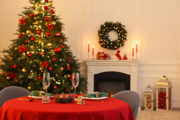 Cozy living room with Christmas tree near fireplace and table served for celebration. Interior design