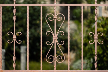 old wrought iron hand rail with floral pattern sat in front of a garden in Europe with a blurry background