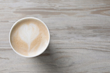 To-go drink. Tasty coffee in paper cup on light wooden table, top view. Space for text