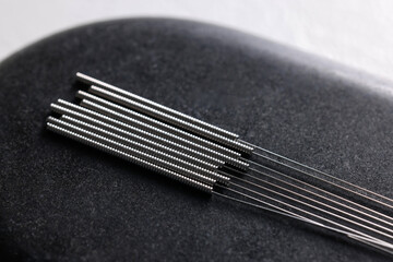 Acupuncture needles on spa stone, closeup view