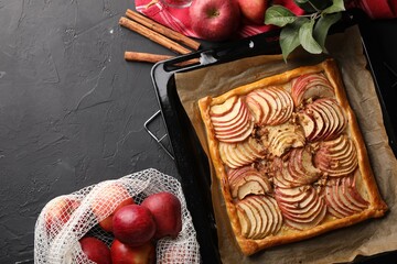 Baking tray with fresh apple galette and fruits on black table, flat lay. Space for text