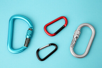 Metal carabiners on light blue background, flat lay