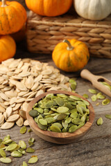 Many fresh pumpkins and seeds on wooden table