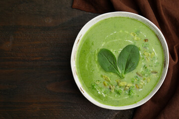 Delicious broccoli cream soup with basil and pumpkin seeds on wooden table, top view. Space for text