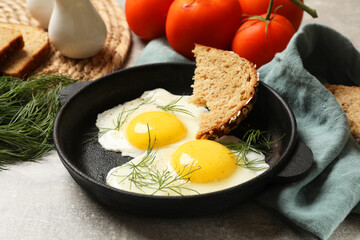 Delicious fried eggs served with bread on grey table