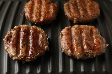 Delicious hamburger patties cooking on electric grill, closeup