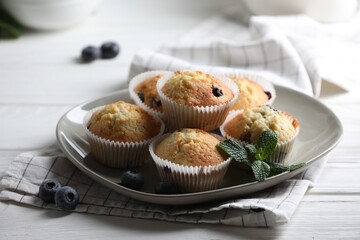Delicious sweet muffins with blueberries and mint on white wooden table