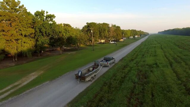 Aerial: Drone Forward Shot Of Pickup Truck Towing Boat In Meadow Against Sky - Bayou, Louisiana