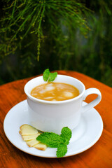 glass mug of hot ginger drink while wrapped in blanket. Close up shot