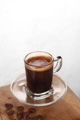 black coffee is served in a clear cup with a wooden base