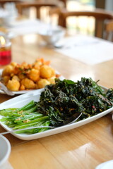 fried cooked green vegetables called kailan served on a restaurant dining table using a white plate