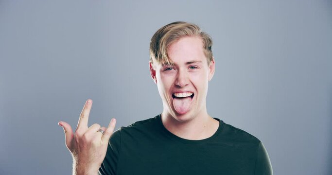 Man, face and rocker hand in studio for head bang dance music, heavy metal on grey background. Male person, devil horns and finger for crazy energetic or concert fun symbol, rock and roll or mockup