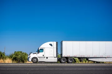 Foto op Plexiglas White big rig bonnet semi truck transporting commercial cargo in dry van semi trailer driving on the flat highway road © vit