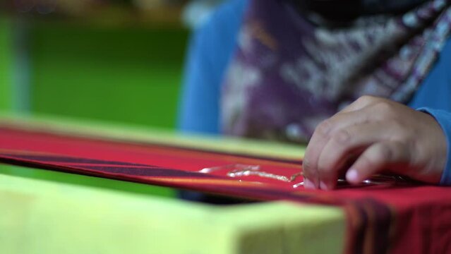 Embroidering gold thread on the Lampung filter cloth.