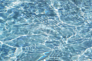 Defocus blurred transparent blue colored clear calm water surface texture with splashes reflection. Trendy abstract nature background. Water waves in sunlight with copy space. Blue watercolor shine.