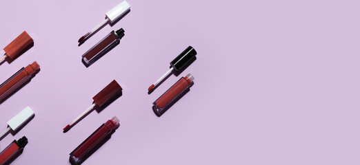 Many liquid lipsticks on lilac background with space for text