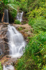 beautiful cascading waterfall over rocks long exposure in Chiangmai Chiang mai mountains northern thailand amongst lush green tropical rainforest