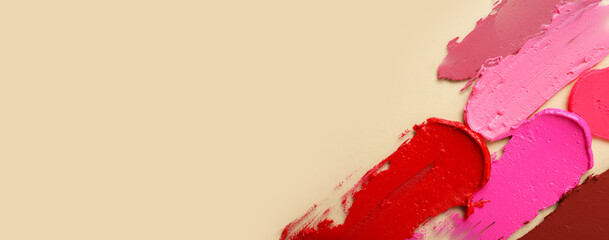 Different lipstick strokes on beige background with space for text, top view