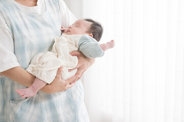 赤ちゃんの出産や検診イメージ( 顔無しの助産師、ママ、保育士、保健師、に抱っこされ寝るベビー）クローズアップ 右にコピースペースあり