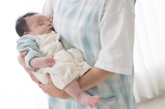 ママや保育士、保健師に抱っこされ寝るベビー服姿の赤ちゃんのイメージ 仰向け　全身