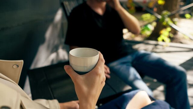A young handsome guy and a girl are sitting on the veranda of a mobile home in camper drinking tea and talking enthusiastically